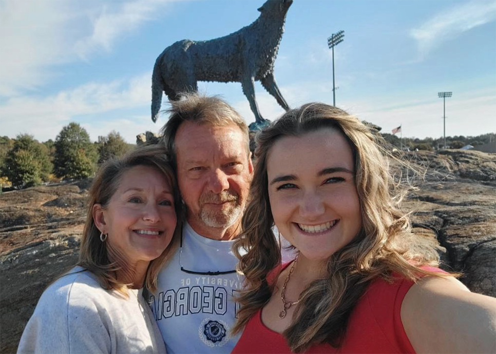 student with parents by wolf statue